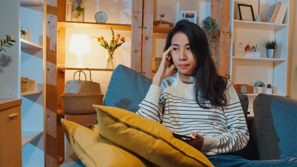 A lonely young woman sitting on a sofa at home