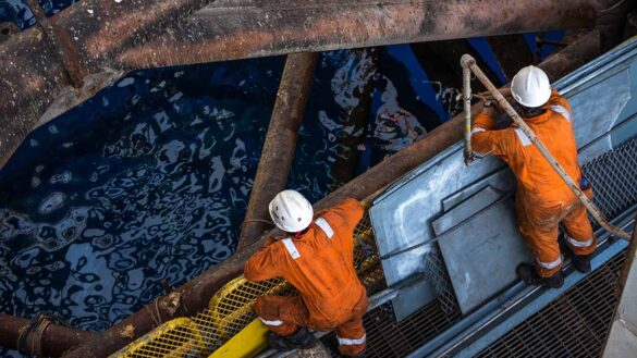 Chevron job cuts. Offshore oil rig workers looking down from a platform into the sea