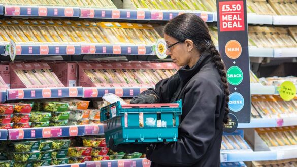 A retail shop assistant restocking a fridge in a supermarket