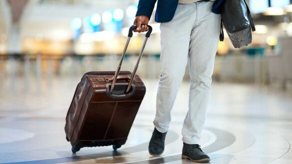 A man walking through an airport, dragging a suitcase