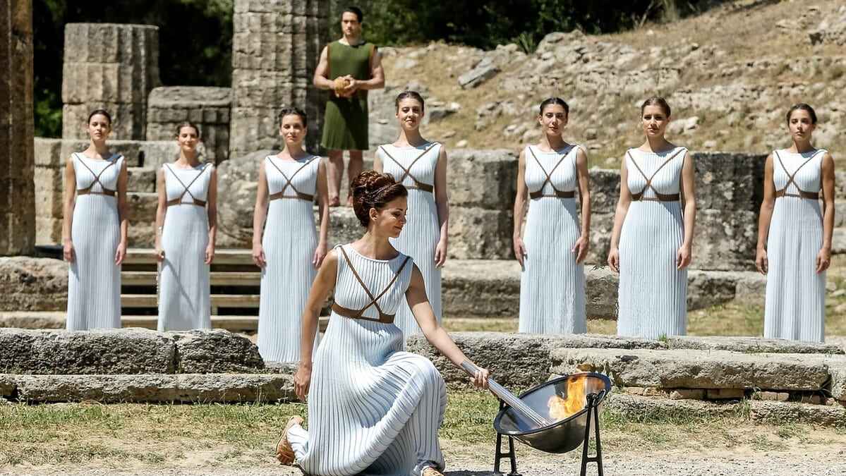 Priestess in ancient Greek clothing lighting the Olympic torch in Olympus, Greece