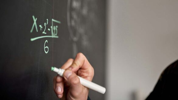 Teacher with autism: Photo shows a teacher writing an equation on a board.