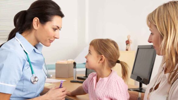 nurse treats young child with mother watching on