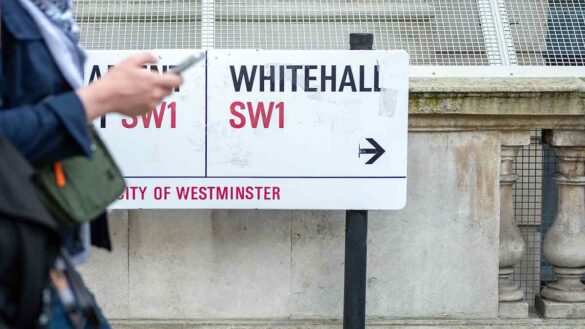 Civil Service office attendance rates 2024. Photo shows a woman using her mobile phone in front of a Whitehall street sign.