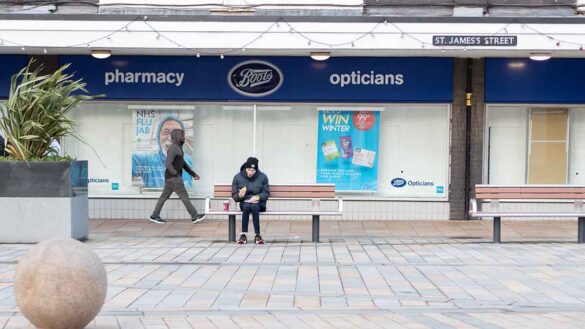 Regional inequality wages. Photo shows man sitting on a bench in Burnley town centre.